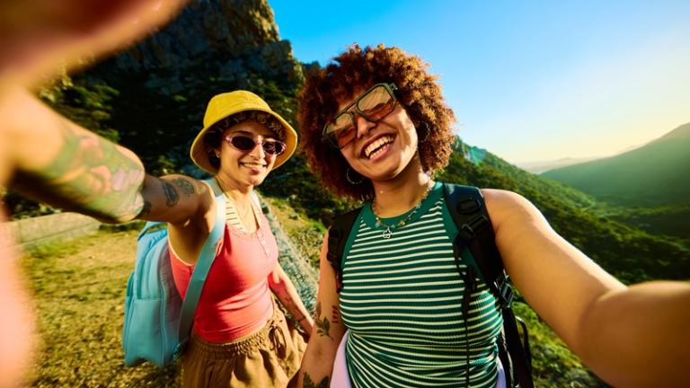 Young women pose for a selfie while hiking outdoors
