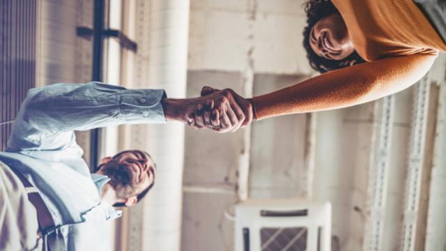 Two people shake hands at a property.