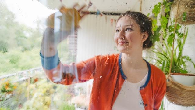 Woman cleans balcony door to her apartment